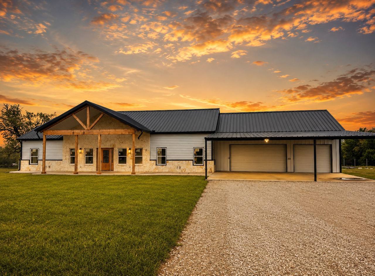 Custom barndominium with metal roof and stone porch at sunset, built by Jaybird Construction